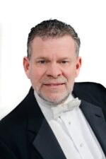 Color headshot of a man in a tuxedo smiling into the camera.